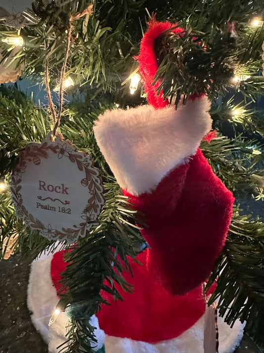 A red and white Christmas stocking hanging from a tree, surrounded by green pine needles and Christmas lights filled with body butters samples